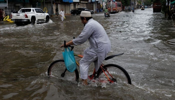 A man rides bicycle along a flooded road, following heavy rains during the monsoon season in Karachi, on July 25, 2022. —Reuters