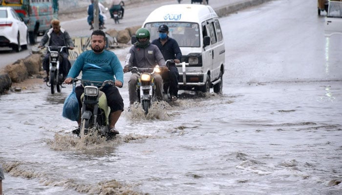 Vehicles passing through rain water at Korangi Road, Karachi. — APP/File