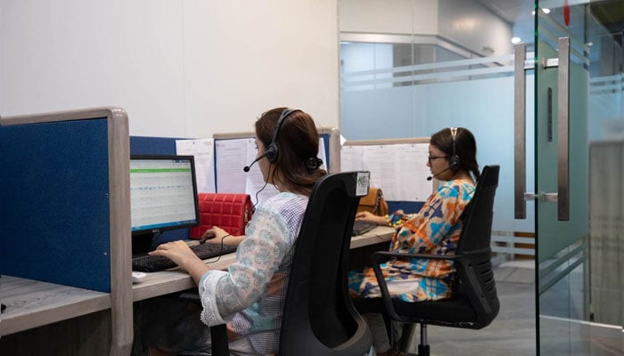 Employees at a health tech company answer calls at the main office in Karachi, Pakistan on April 14, 2022. — Reuters