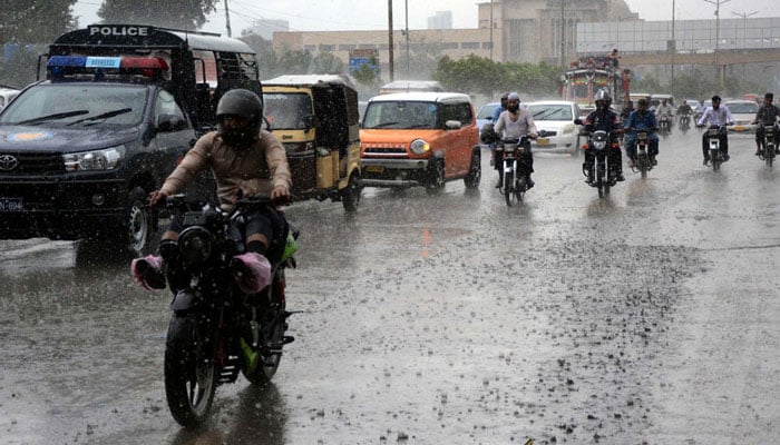 Commuters are passing through a road during heavy downpour of monsoon season, at Shahrah-e-Faisal road in Karachi on Tuesday, July 9, 2024. — PPI