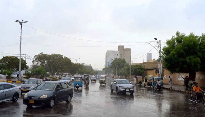 Commuters passing through a road during heavy downpour of monsoon season, at Governor House road in Karachi on July 9, 2024. — PPI