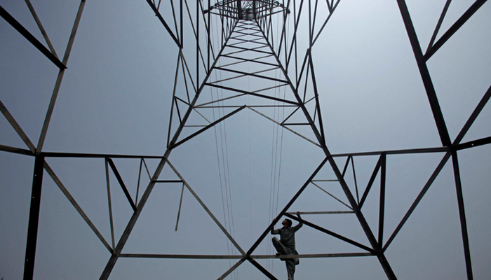 A worker of Pesco climbs up a high-voltage pylon in Peshawar, August 7, 2017. — Reuters