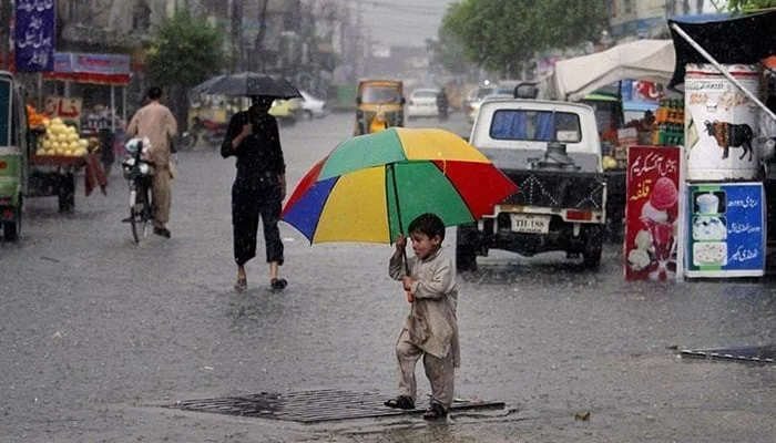 A child carries an umbrella as he walks on the road during rain. — AFP