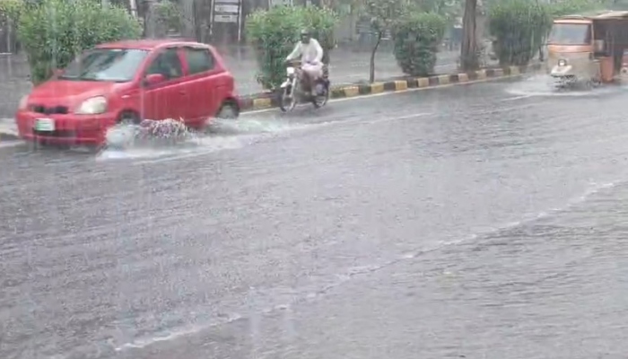 People on their way on a road during heavy monsoon rain in Lahore on July 12, 2024. —Reporter