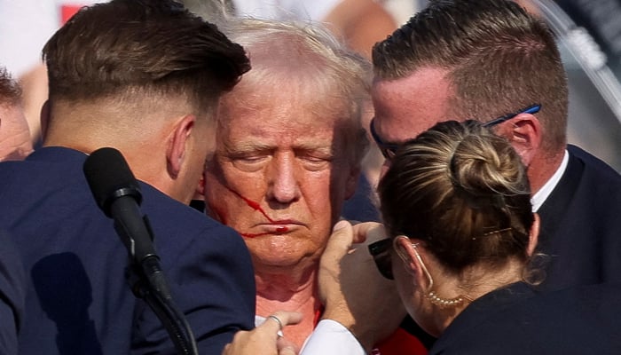 Republican presidential candidate and former US President Donald Trump is assisted by the Secret Service after gunfire rang out during a campaign rally at the Butler Farm Show in Butler, Pennsylvania, US, July 13, 2024. — Reuters