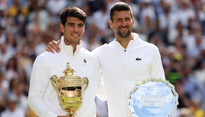 Spains Carlos Alcaraz and runner up Serbias Novak Djokovic pose for a picture with their trophies after the mens singles final on July 14, 2024. — Reuters