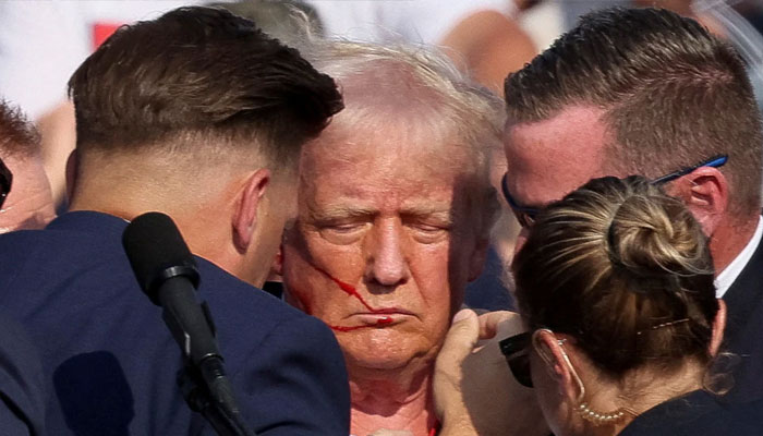 Republican presidential candidate and former US President Donald Trump with his bloodied face is assisted by the Secret Service as multiple shots rang out during a campaign rally at the Butler Farm Show in Butler, Pennsylvania, US, July 13, 2024. — Reuters