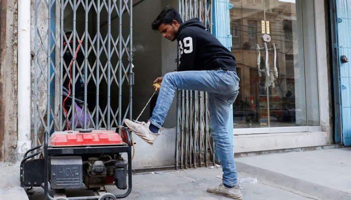 A man starts a generator outside his shop in Karachi during a country-wide power breakdown. — Reuters