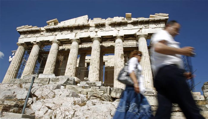 Tourists walk past the Parthenon on Acropolis hill in Athens May 18, 2010. — Reuters