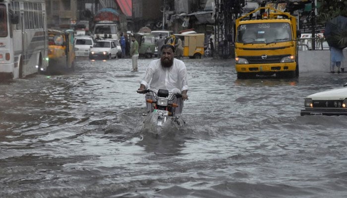 A man rides on a motorcycle amid flood waters along a road during the monsoon season in Rawalpindi, Pakistan July 19, 2023. — Reuters