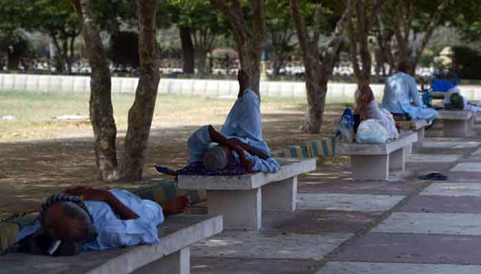 Men rest under the shade of a tree during the heat wave in Karachi. — AFP/File