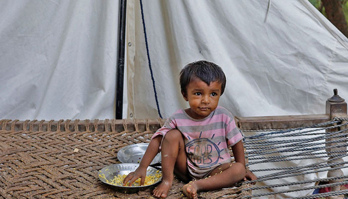 A boy, whos family displaced because of the floods, eats boiled rice while sitting outside his family tent while taking refuge in a camp, in Sehwan, Pakistan, on September 30, 2022. — Reuters