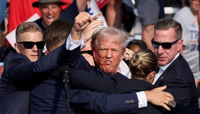 Former president and Republican candidate Donald Trump being assisted by the Secret Service after an assassination was attempted on his life during a campaign rally at the Butler Farm Show in Butler, Pennsylvania on July 13, 2024 — Reuters