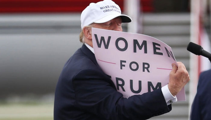 Donald Trump holds a sign that reads Women for Trump during his 2016 presidential campaign, which was beset by scandal over his treatment of women. — AFP