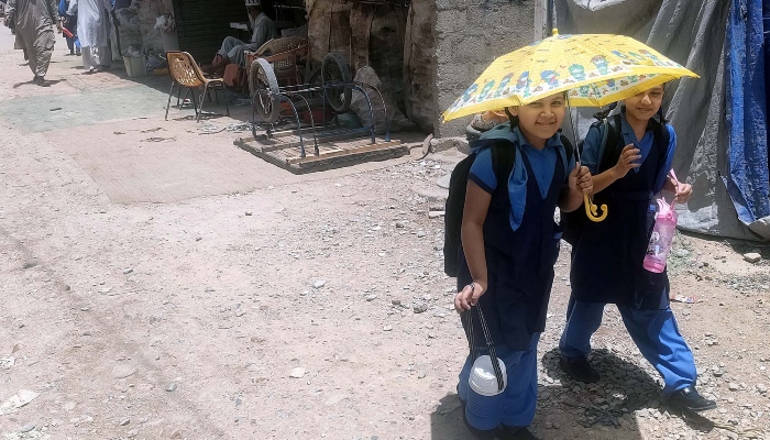 Schoolchildren carrying an umbrella to protect themselves from scorching sun during a hot weather in Malir area of Karachi on May 29, 2024. —PPI