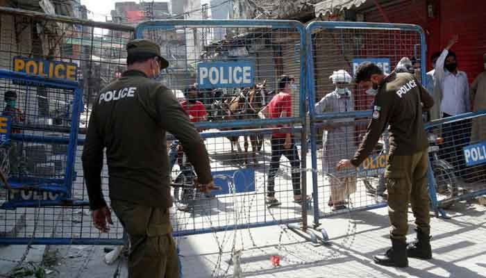 The picture shows police personnel putting barriers on a road. — APP/File