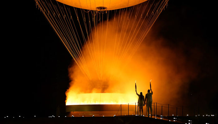 The torchbearers Marie-Jose Perec and French judoka Teddy Riner arrive to light the cauldron and open the 2024 Olympic games. — AFP