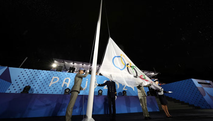 The Olympic flag is being raised by the officials. —Reuters