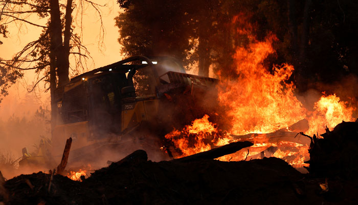 A bulldozer is used to put out flames off Highway 32 near Forest Ranch, California, US on July 26, 2024.