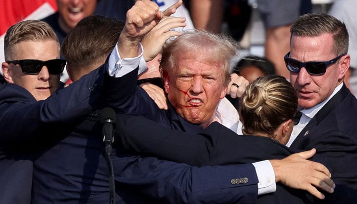 Former president of the US and Republican presidential election candidate Donald Trump surrounded by Secret Service after a bullet grazed his ear during his campaign rally in Butler, Pennsylvania, US on July 13, 2024. — Reuters