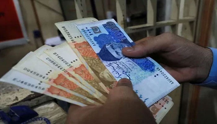 A representational image showing a person holding Pakistani rupees. — Reuters/File