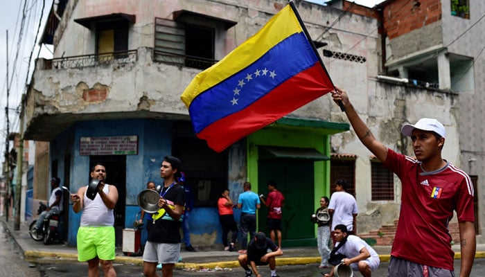 A man waves a Venezuela flag as other residents bang pots to protest against the presidential election results at Los Magallanes de Catia neighbourhood, in Caracas, Venezuela on July 29, 2024. — Reuters