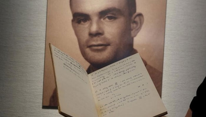 A notebook of British mathematician and pioneer in computer science Alan Turing is displayed in front of a photo of him during an auction preview in Hong Kong March 19, 2015. — Reuters