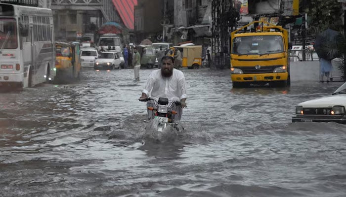 A man rides on a motorcycle amid flood waters along a road during the monsoon season in Rawalpindi, July 19, 2023. — Reuters