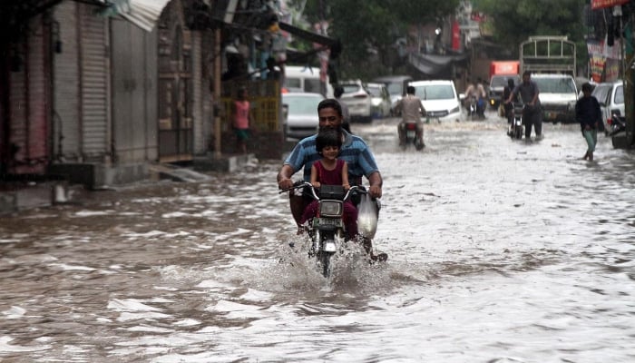 Vehicles passing through rain water accumulated on the road after heavy rain that experienced in Lahore on August 1, 2024. — APP