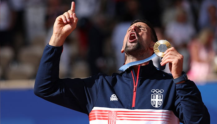 Gold medallist Novak Djokovic of Serbia gestures while holding his medal. — Reuters