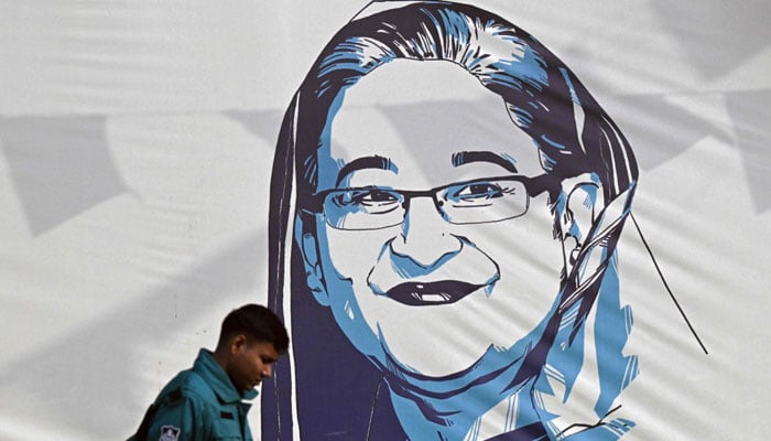 A policeman walks past a portrait of Bangladesh´s Prime Minister Sheikh Hasina, in Dhaka on January 8, 2024. — AFP