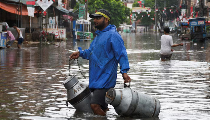 A man carries containers along a flooded street after heavy rainfall in Hyderabad, Sindh, Pakistan on August 24, 2022. — Reuters