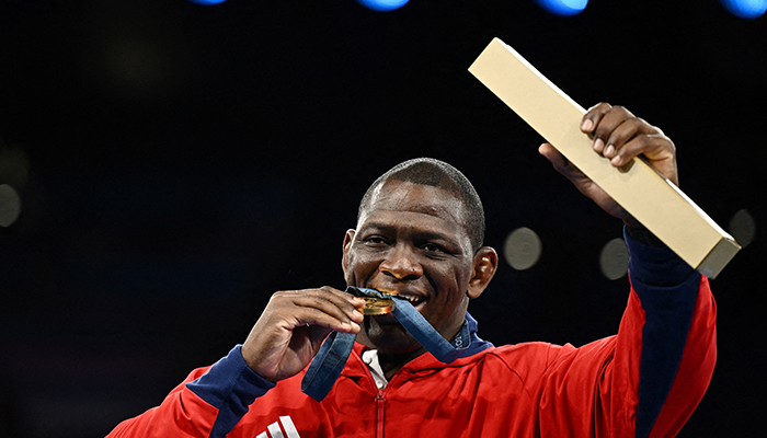 Gold medallist Mijain Lopez Nunez of Cuba bites his medal after becoming the first athlete in any sport to win the same event in five consecutive Olympics. — Reuters