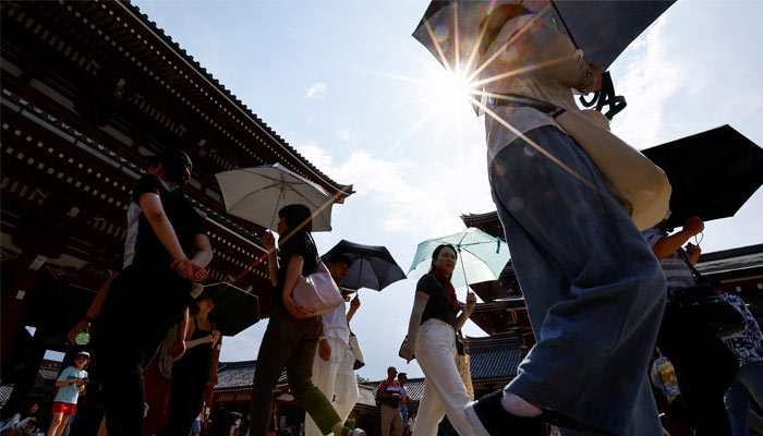 People holding umbrellas in scorching heat. — Reuters/File