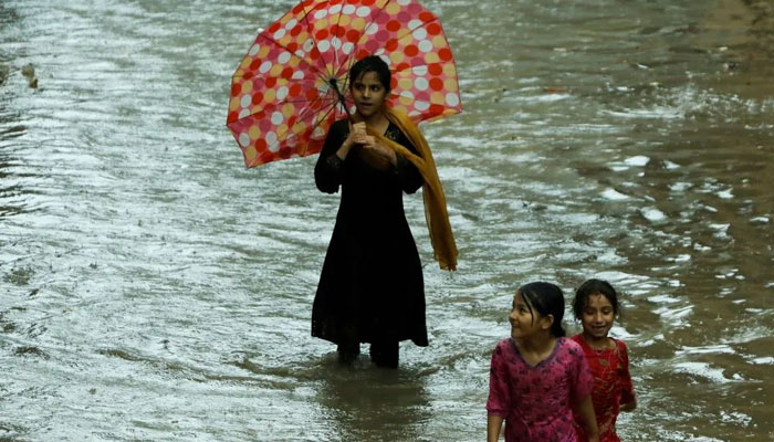 Children walk through a flooded street during monsoon season in Peshawar, July 21, 2022. — Reuters