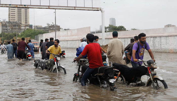 Residents commute through a flooded road during the monsoon season in Karachi on July 9, 2022. — Reuters