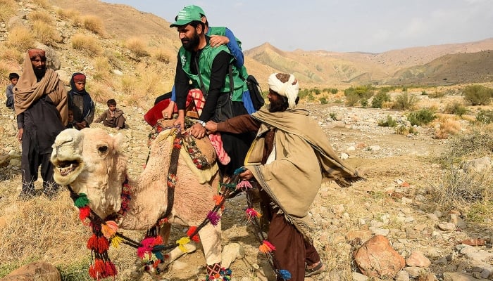 Census officials from the Pakistan Bureau of Statistics ride a camel to collect information from Marri tribespeople living in the remote mountainous area of Mawand as part of a national census in Kohlu district, Balochistan, on March 23, 2023. —AFP