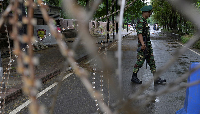 A security force personnel walks behind concertina wire placed across a road next to the residence of former Bangladeshi prime minister Sheikh Hasina, days after her resignation as the premier of the country, in Dhaka, August 8, 2024. — Reuters