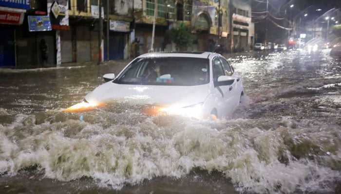 A vehicle drives along a flooded street following heavy rains during the monsoon season in Karachi on July 24, 2022. — Reuters