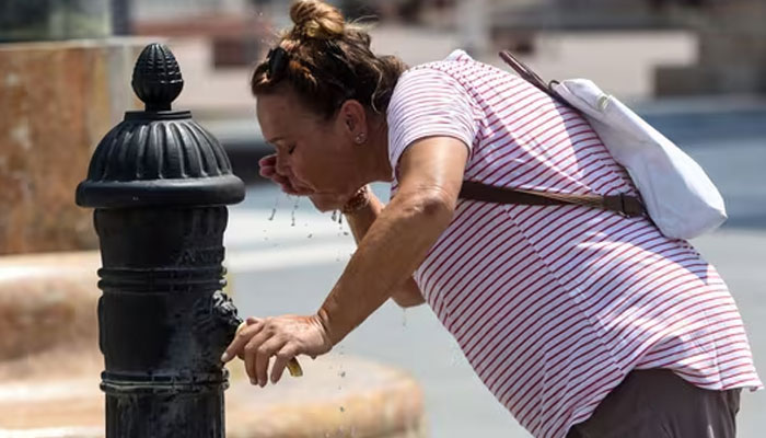 A woman cools off amid scorching heat in Skopje, Macedonia. — AFP/File