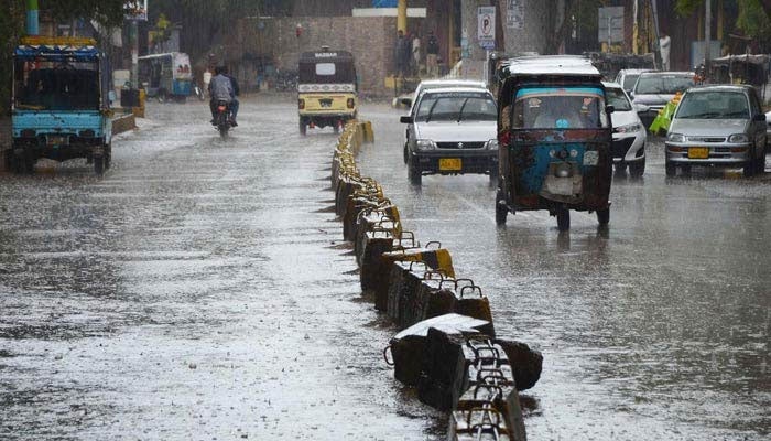 Vehicles pass through rain water during the heavy rain in Karachi on March 24, 2023. — INP