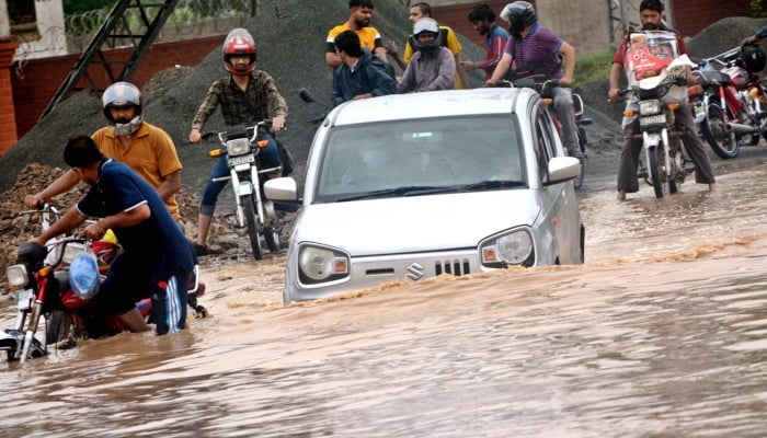 A car is trapped on a road flooded with rainwater, highlighting the city’s failing drain infrastructure after torrential rains, in Lahore on August 8, 2024. —APP