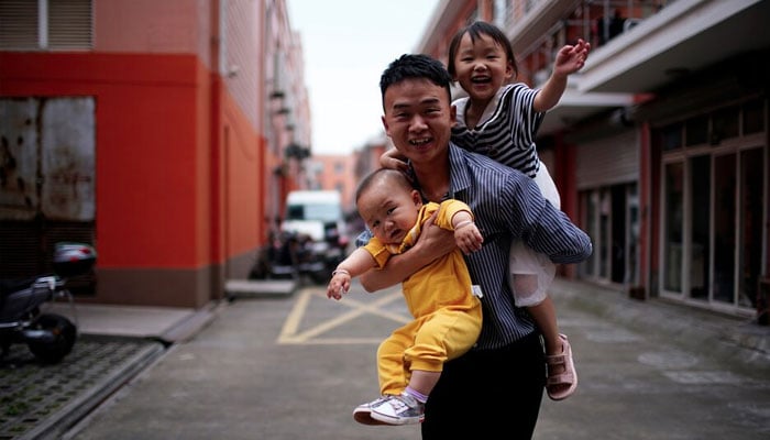 Sun Yans husband plays with their two children on the outskirts of Shanghai, China June 3, 2021. — Reuters