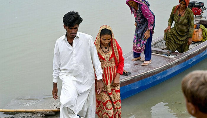 Newly married underage monsoon bride Amina (2L), with her husband Mohammad Usman (L) arrives at the Khan Muhammad Mallah village in Dadu district. – AFP