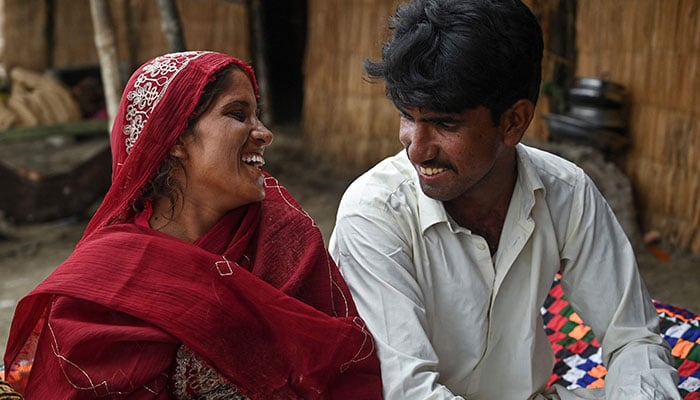 Sabahi Ali (L), a monsoon bride who was married underage, reacts alongside her husband Dilsher Ali at Khan Muhammad Mallah village, Dadu district on August 3, 2024. – AFP