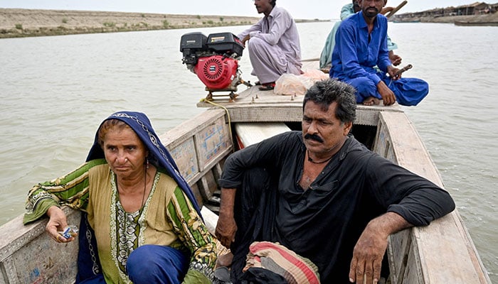 Hakim Zaadi (L), village matron and mother of Najma Ali (not pictured), a monsoon bride who was married underage, rides a boat with her husband Babiho Mallah (C), along a canal at the Khan Muhammad Mallah village in Dadu district. – AFP