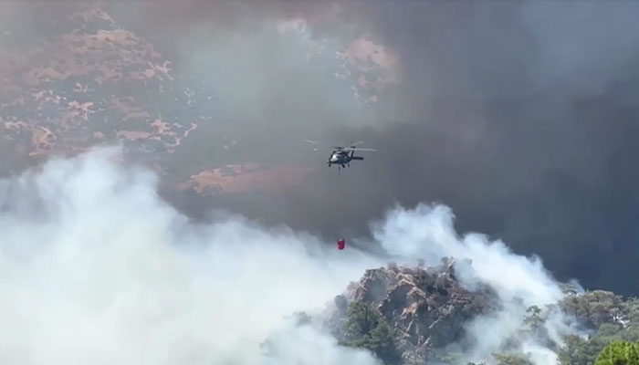 A helicopter fly through thick smoke to douse wildfire in western Turkey on August 17, 2024. — Reuters