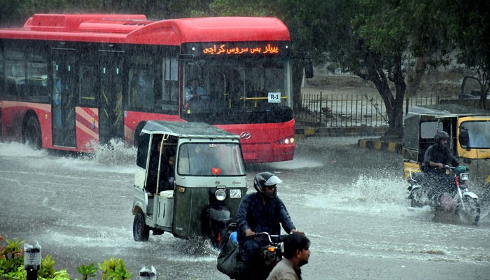 Commuters struggle to move forward in a flooded street after heavy monsoon rain in Karachi. — Online/File