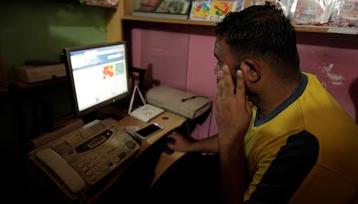 A man sits infront of a computer at an internet cafe in Islamabad. — Reuters/File