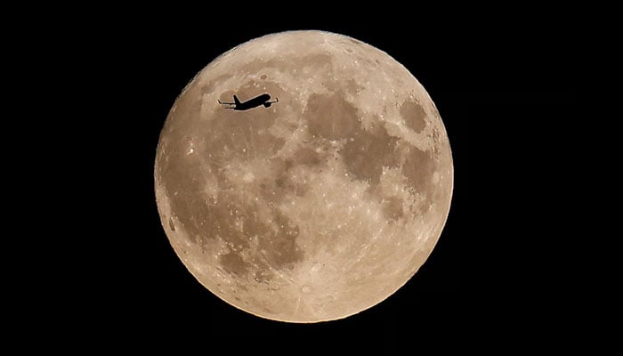 An aircraft flies over London and in front of the the super moon, know as the Blue Moon, in London, Britain. — Reuters/File